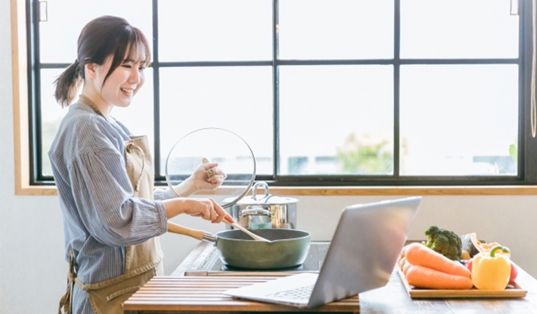 PCを見ながら調理する女性