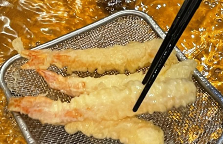 油で揚げられているエビの天ぷら