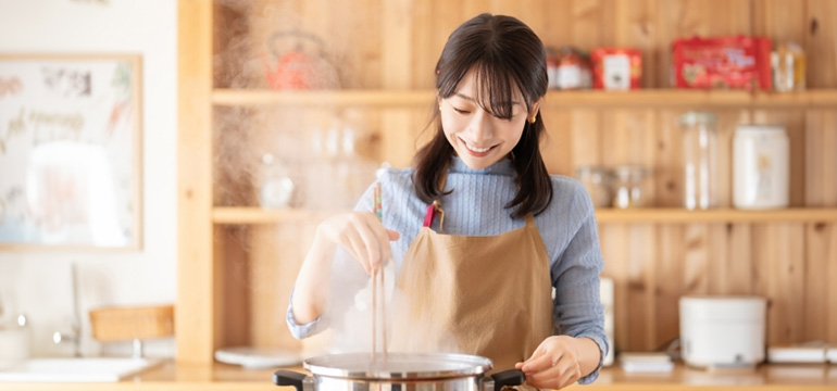 笑顔で料理をする女性の画像