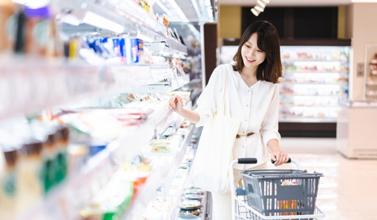 スーパーの陳列棚の商品を眺めている女性の買い物客