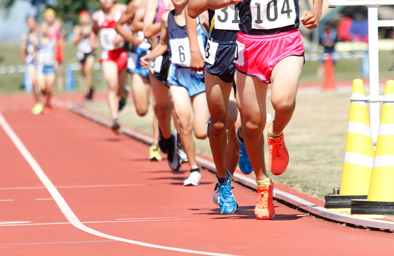 陸上競技大会で長距離走で走る集団
